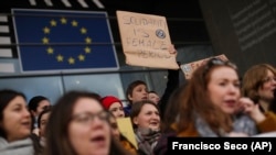 Wanawake wakiwa na mabango yao juu wamekusanyika nje ya Bunge la Ulaya wakipinga uonevu dhidi ya tofauti ya mishahara baina yao na wanaume, uvunjifu wa amani na kukosekana haki katika maeneo mengi, mjini Brussels, Ijumaa, Machi 8, 2019.