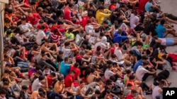 Los menores no acompañados que cruzaron a España aparecen reunidos afuera de un almacén utilizado como refugio temporal en el enclave español de Ceuta, cerca de la frontera entre Marruecos y España, el miércoles 19 de mayo de 2021.