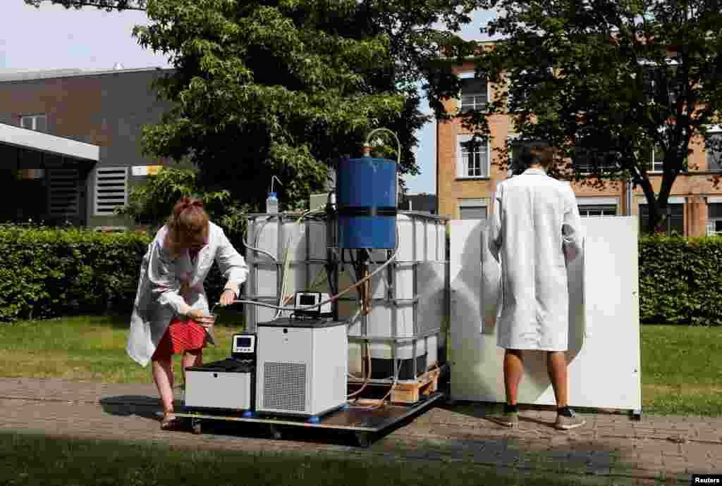 Belgian scientists Marjolein Vanoppen and Sebastiaan Derese (R) demonstrate the use of a machine that uses solar energy to turn urine into drinkable water and fertilizer, at the University of Ghent, Belgium.