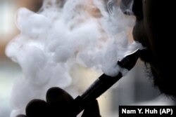 In this April 23, 2014 file photo, a man smokes an electronic cigarette in Chicago. On Friday, Aug. 30, 2019, the Centers for Disease Control and Prevention said they are investigating more cases of a breathing illness associated with vaping.