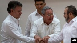 Cuban President Raul Castro, center, encourages Colombian President Juan Manuel Santos, left, and FARC Commander Timoleon Jimenez to shake hands after the last obstacle to a peace deal was overcome at talks in Havana, Sept. 23, 2015. 