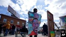 Un hombre sostiene un cartel en la Plaza George Floyd, en Minneapolis, el miércoles 21 de abril de 2021, un día después de que el exagente de policía Dereck Chauvin fuera declarado culpable por la muerte de Floyd en 2020.