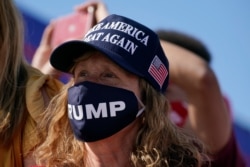 A supporter watches as President Donald Trump speaks during a campaign rally at Wittman Airport in Oshkosh, Wis., Aug. 17, 2020.