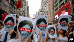 Protesters hold pictures of Hong Kong Chief Executive Carrie Lam as protesters march along a downtown street against the proposed amendments to an extradition law in Hong Kong Sunday, June 9, 2019.19.