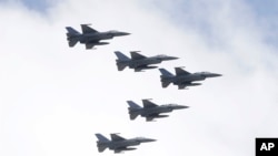 ထိုင်ဝမ်အမျိုးသားနေ့အခမ်းအနားမှာ တိုင်ပေမြို့က သမ္မတအဆောက်အဦးအထက်မှာ ဝဲပျံနေတဲ့ အမေရိကန်လုပ် F-16 တိုက်လေယာဥ်များကို တွေ့ရစဥ်။ (အောက်တိုဘာ ၁၀၊ ၂၀၁၂) 