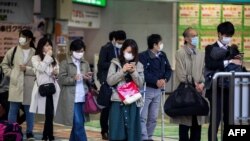 Koronavirusga qarshi yuziga niqob taqib olgan odamlar poyezd kutmoqda, Tokio, Yaponiya, 2020-yil, 6-aprel.