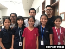 Tes Putthira, technical mentor for coding, takes a photo with two other mentors, Keang Searn (middle) and Yim Borann (right), behind the five members of the “Cambodia Identity Product” girls team during a 12-weekend training at the Cambodia-Korea Cooperation Center in Phnom Penh. (Courtesy of Technovation Cambodia)