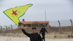 2024 年12 月8 日，在敘利亞首都大馬士革被反政府武裝攻佔後，一名敘利亞庫爾德人在敘利亞東北部卡米甚利機場附近揮舞人民保護部隊（YPG）的旗幟。