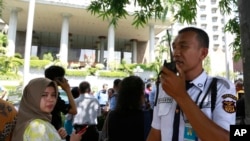 An Indonesian security officer talks on his radio as people evacuate from buildings after an earthquake in Jakarta, Indonesia, Jan. 23, 2018.