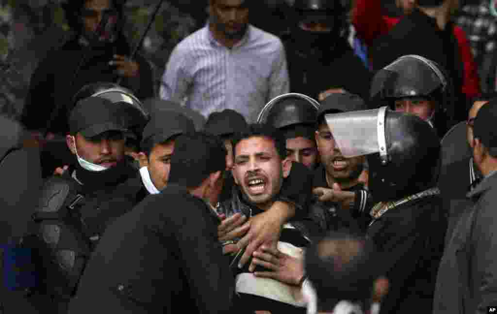 Egyptian riot police arrest a man during clashes with protesters near Tahrir Square in Cairo, Egypt, January 30, 2013. 