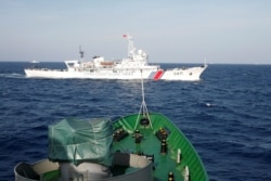 FILE - A ship (top) of the Chinese Coast Guard is seen near a ship of the Vietnam Marine Guard in the South China Sea, about 210 km ff shore of Vietnam May 14, 2014.