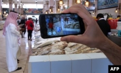 A gamer uses the Pokemon Go application on his mobile in the main fish market in Kuwait City on July 14, 2016.