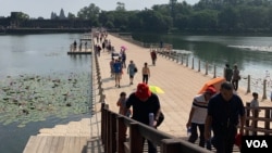 ភ្ញៀវទេសចរណ៍ចូលទស្សនាប្រាសាទអង្គរវត្ត ដោយដើរឆ្លងស្ពាននៅមុខប្រាសាទអង្គរវត្ត នៅក្នុងខេត្តសៀមរាប កាលពីថ្ងៃទី៩ ខែវិច្ឆិកា ឆ្នាំ២០១៩។ (ធីតា វីន/VOA)