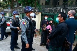 Myanmar police talk to people gathering outside the Kamayut court in Yangon, March 12, 2021.