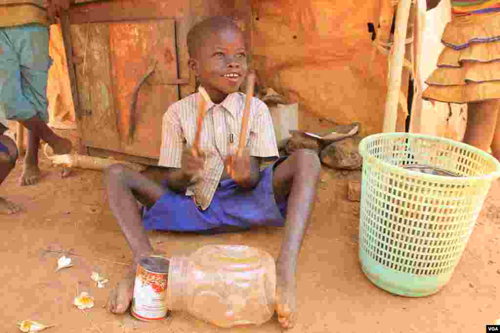 A young IDP play improvised drum at the St. Mary Help of Christians Cathedral in Wau, Western Bahr el Ghazal, where his family is living, Dec. 8, 2016. (VOA/Jill Craig) 
