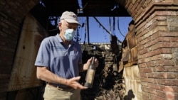Dario Sattui holds one of the more than 100,000 bottles of wine lost when fire devoured a building near his Tuscan-style castle, Castello di Amorosa in Calistoga, Calif., on Thursday, Oct. 15, 2020. (AP Photo/Eric Risberg)