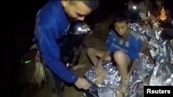 Les enfants de l'équipe de football pris au piège dans la grotte de Tham Luang sont soignés par un infirmier à Chiang Rai, Thaïlande, dans cette image extraite d'une vidéo du 3 juillet 2018 par la marine thailandaise.