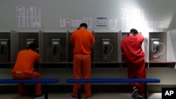 Inmigrantes detenidos en EE.UU., muchos de ellos centroamericanos, usan teléfonos públicos en un centro de detención en California, el 28 de agosto de 2019.