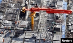 FILE - Laborers work at the construction site of an apartment building in Hanoi, July 1, 2015.