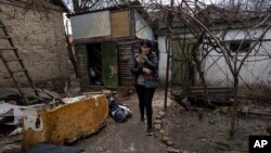 Una mujer camina con un gato entre los cadáveres de su esposo y un hermano en Bucha, Ucrania, el 4 de abril de 2022.