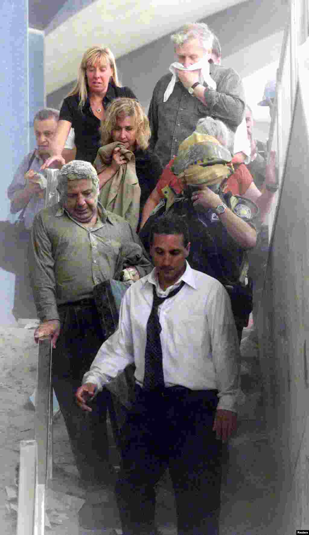 People walk away from the World Trade Center tower. Three hijacked planes crashed into U.S. landmarks, destroying both of New York's mighty twin towers and plunging the Pentagon in Washington into flames.