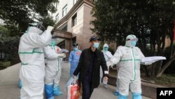 ក្រុម​គ្រូពេទ្យ​ជួយ​អ្នក​ជំងឺ​ដែល​មាន​ផ្ទុក​វីរុស​កូវីដ​១៩ នៅ​ពេល​ចាក​ចេញ​ពី​មន្ទីរ​ពេទ្យ​នៅ​ទីក្រុង​វូហាន ដើម្បី​ធ្វើ​ដំណើរ​ទៅ​មន្ទីរ​ពេទ្យ​ Huoshenshan នៅ​ខេត្ត Hubei ប្រទេស​ចិន កាល​ពី​ថ្ងៃ​ទី​៤ មីនា ២០២០។