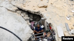 Palestinac sjedi među ruševinama na mjestu izraelskih napada na kuće u Khan Younisu