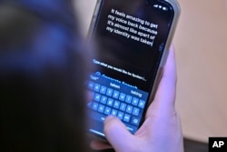 Alexis Bogan types a response to a reporter's question with an app which approximates her lost voice, Thursday, March 11, 2024, at Rhode Island Hospital in Providence, R.I. (AP Photo/Josh Reynolds)