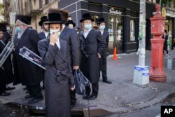 Sejumlah anggota komunitas Yahudi Ortodoks di sebuah pojokan jalan di kawasan Borough Park di Brookly, New York, 11 Mei 2021. (Foto: John Minchillo/AP Photo)
