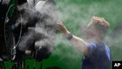 Un espectador se refresca durante una jornada de entrenamiento previa al Abierto de Australia en Melbourne Park, Melbourne, Australia, 12 de enero de 2024. 