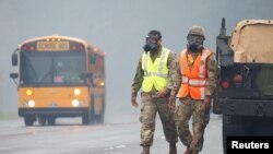 Hawaii National Guard soldiers wear masks to protect themselves from volcanic gases during ongoing eruptions of the Kilauea volcano in Hawaii, May 17, 2018.