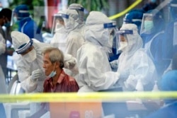 A health worker collects sample for new coronavirus testing from a man at the newly locked down area in Kuala Lumpur, Malaysia, on Friday, May 15, 2020.