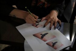 In this Saturday, November 9, 2019, photo, Suraya Shaheedi, 26, Tattoo artist, takes a copy of tattoo before a pierced tattoo to her male customer in Kabul, Afghanistan.
