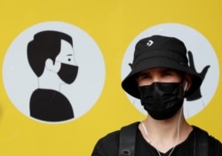FILE - A man wearing a protective face mask amid the outbreak of the coronavirus disease (COVID-19) stands in front of a social poster in central Kyiv, Ukraine July 30, 2020. (REUTERS/Gleb Garanich/File)