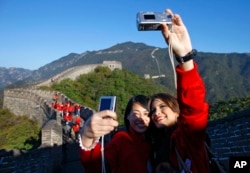 Miss World contestants Kamilla Salgado of Brazil, right, and Tang Xiao of China take a photo of themselves while visiting the Mutianyu Great Wall in Beijing, China Tuesday, Oct. 5, 2010.