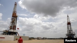 Un trabajador de un campo petrolero camina junto a las plataformas de perforación en un pozo de petróleo operado por la petrolera estatal de Venezuela PDVSA, en el rico cinturón petrolero del Orinoco, el 16 de abril de 2015.
