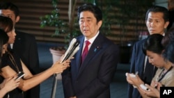 Japan's Prime Minister Shinzo Abe, center, speaks to reporters at his official residence in Tokyo, July 17, 2015. 
