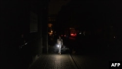 Жінка у Києві йде темрявою під час часткового відключення електроенергії, що спричинено російськими ударами по енергетичній інфраструктурі, 5 червня 2024 р. Roman PILIPEY/AFP