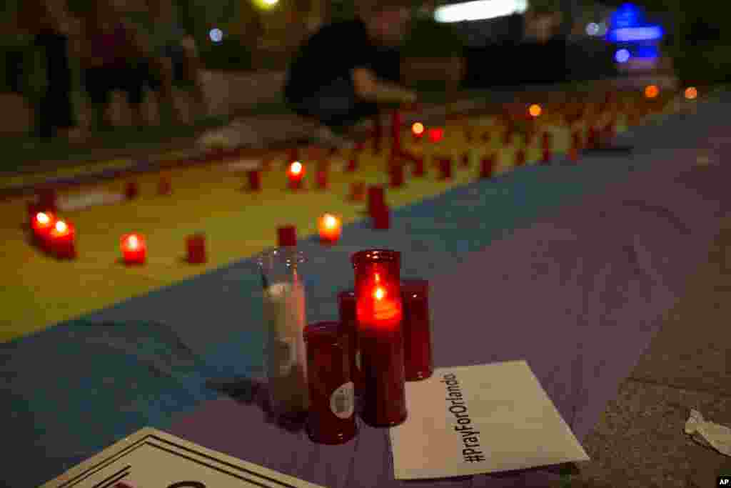 Man lights candles atop rainbow flag in solidarity with Pulse Orlando victims, Madrid, Spain, June 12, 2016.