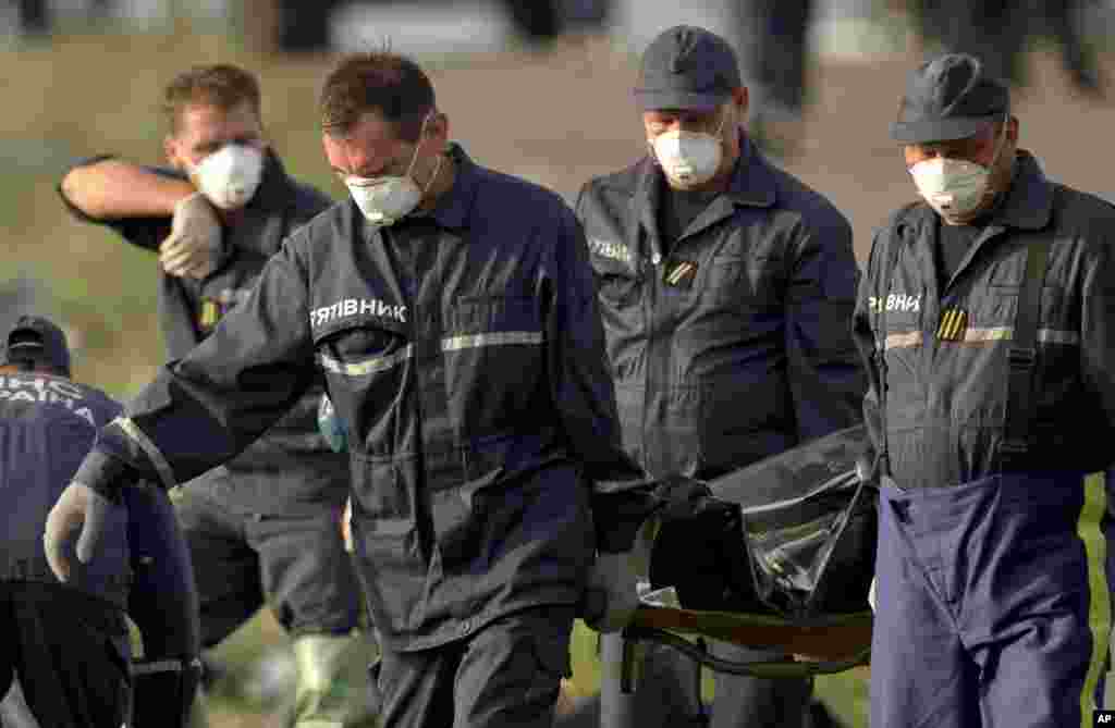 Emergency workers carry the body of a victim at the crash site of Malaysia Airlines Flight 17 near the village of Hrabove, eastern Ukraine, July 19, 2014.