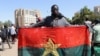 Homem ergue bandeira do Burkina Faso durante uma manifestação de apoio aos militares após a detenção do Presidente Roch Kabore. 24 Janeiro 2022