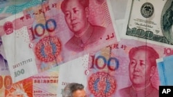 FILE - In this Aug. 6, 2019, photo, a man walks by a money exchange shop decorated with Chinese yuan bank notes and other countries' currency at Central, a business district in Hong Kong. 
