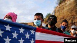 Un grupo de migrantes hondureños muestra una bandera de Estados Unidos mientras avanza en caravana por el estado de Vado Hondo, en Guatemala, el 18 de enero de 2021.