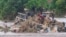 In this image made from video, people stand on an overturned vehicle swept by flooding waters in Chikwawa, Malawi, Jan. 25, 2022.