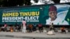 People sit under a billboard with a congratulatory message of the President-Elect Bola Ahmed Tinubu of the All Progressives Congress in Lagos, Nigeria, March 5, 2023.