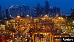 The skyline of Singapore's central business district is seen at dusk as operations continue at a PSA International port terminal in Singapore September 25, 2013. Connected to more than 600 ports in some 120 countries, Singapore is one of the world's busie
