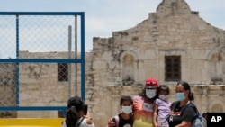 Visitantes posan frente a la fachada del Álamo, en San Antonio, Texas, mientras portan tapabocas. Los casos de COVID-19 se han elevado en Texas y el gobernador animó a las personas a usar tapabocas en espacios públicos.