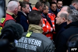 German Chancellor Olaf Scholz, right, talks to rescuers during a visit to the site of a car-ramming attack on a Christmas market in Magdeburg, Germany, on Dec. 21, 2024.