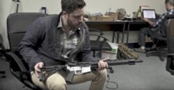 Gun rights activist Cody Wilson, director of Defense Distributed, holds a weapon at his Ghost Gunner factory in Austin, Texas. (YouTube)