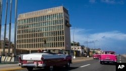 ARCHIVO - Turistas viajan en autos convertibles clásicos en el Malecón junto a la Embajada de Estados Unidos en La Habana, Cuba, en octubre de 2017. 